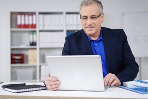 geschftsmann schaut lchelnd auf seinen laptop
