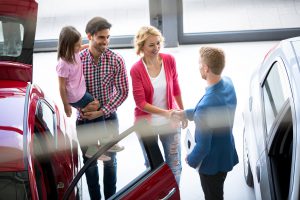 Car dealer offering a car to smiling family